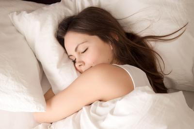 A-young-woman-sleeps-soundly-in-bed-hugging-a-pillow.