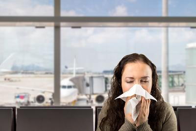 Traveler sneezing in airport terminal due to allergies