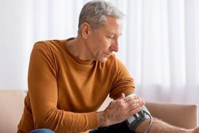 Elderly man monitoring blood pressure with cuff