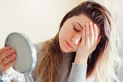 Woman feeling dissapointed after looking at the mirror