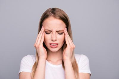 Woman suffering from migraine holding her head