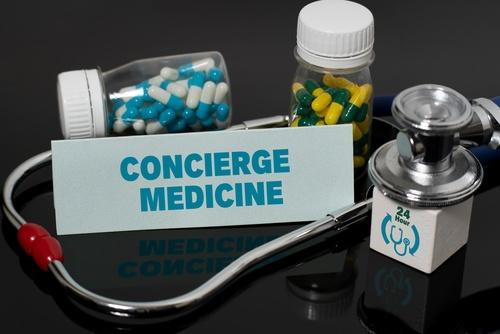 Paper with the words "Concierge Medicine" placed next to medicines and a stethoscope.