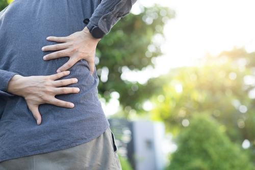 Man holding his lower back in pain outdoors