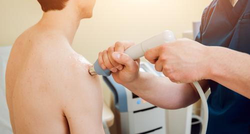 Shockwave therapy session for a man with shoulder pain.