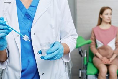 Doctor-with-Pap-Smear-Test-Kit-with-Woman-in-Back