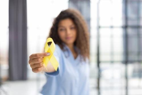 A woman holding a yellow ribbon to raise awareness for endometriosis.
