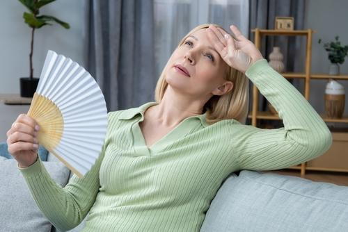 A woman showing discomfort from hot flashes caused by menopause.