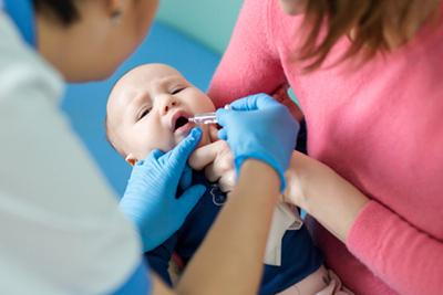Toddler giving a drops with the doctor and mother