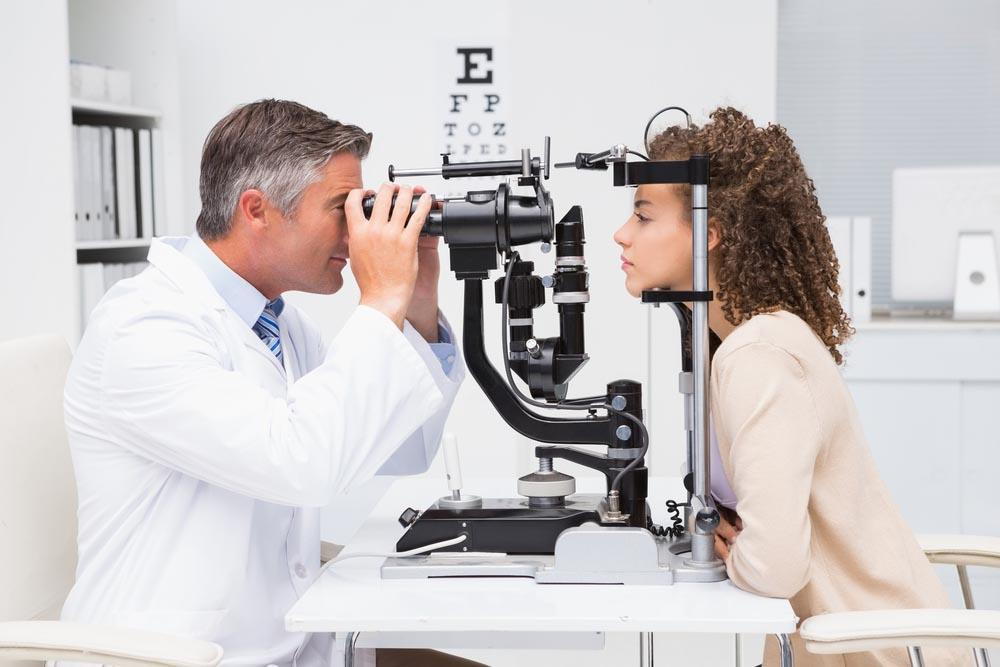 eye doctor looking at a girls eyes through an eye machine- Guide To Choosing The Right Reading Glasses For You In Pensacola - Fifty Dollar Eye Guy 5328 N Davis Hwy Pensacola, FL 32503 (850) 434-6387