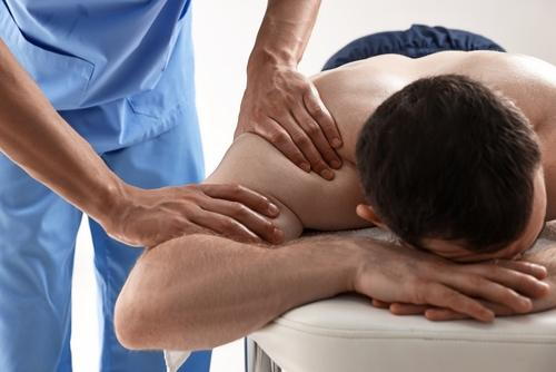 Male client receiving a chiropractic massage to relieve shoulder discomfort