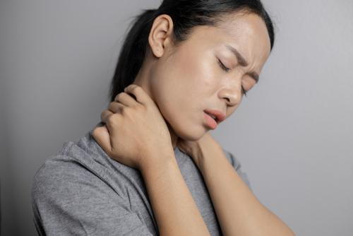 Woman holding her neck in pain at home.