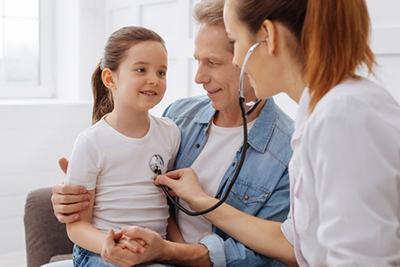 Doctor checking the young girls health with her dad