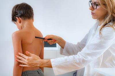 Doctor checking the back of a young boy