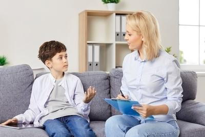 Young boy talking to a therapist on sofa