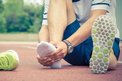 Man-sitting-on-track-holding-injured-foot