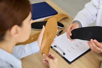 Patient hold a Custom Orthotics with the doctor explaining