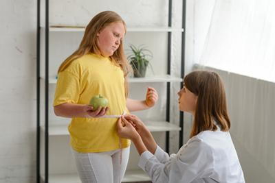 Young girl undergoing a medical waist measurement during pediatric obesity checkup.