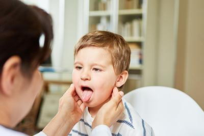 Doctor checking the young boy throat from Tonsillitis