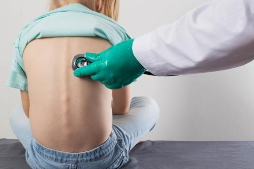 A pediatrician using a stethoscope to check a child's lungs for signs of pneumonia.