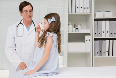 Young girl suffering from asthma with the doctor beside her