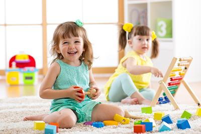 Two little girls playing on play room with a smile