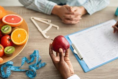 Nutritionist or physician using an apple as a symbol of healthy food choices during patient consultation.