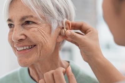 Audiologist assisting senior woman with hearing aid fitting