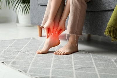 Woman with arthritis clutching aching ankle during flare-up