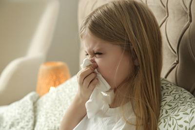 Sick child with a runny nose sitting in bed