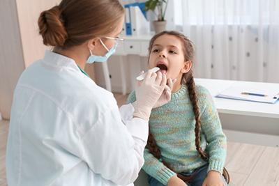 Doctor checking the young girl for Tonsillitis