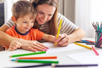 Mother and son coloring a drawing on table.