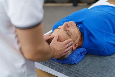 Chiropractor performing manual therapy on a man to treat tension headaches.