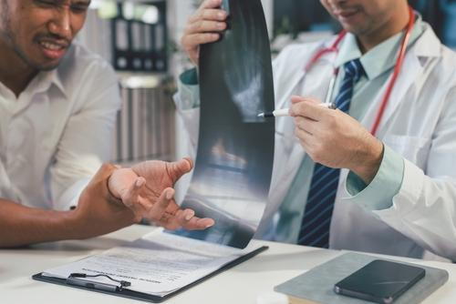 Doctor examining X-ray results of a man's fractured wrist.