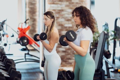 Two women lifting dumbbells during a functional fitness training session