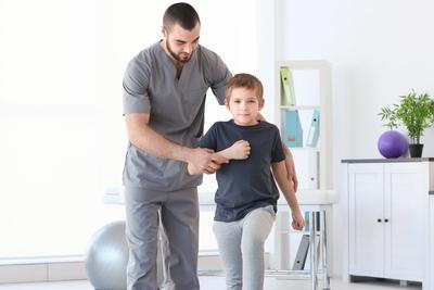 Clinical-assistant-checking-the-young-boy-flexibility-on-clinic.