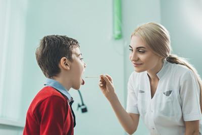 Pediatrician checking the throat of a young boy