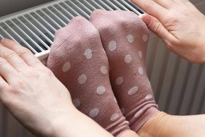 Person in polka dot socks warming feet on heater