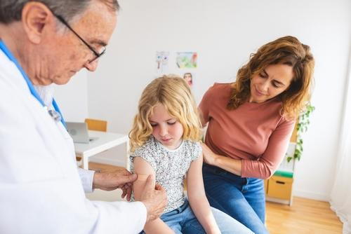 Doctor-injecting-a-vaccine-to-a-little-girl-with-the-mother-beside-her.