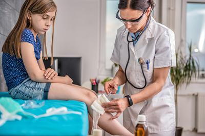 Doctor treating the wound of a young girl on clinic