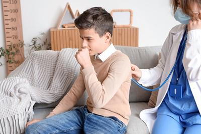Doctor checking the young boy with cough