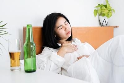 Alcohol-induced heartburn affecting woman lying in bed