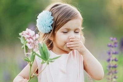 Young girl allergy in flowers sneezing outside