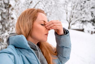 Woman holding her nose outside in winter season