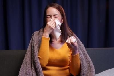 Woman feeling discomfort wiping her nose with comforter