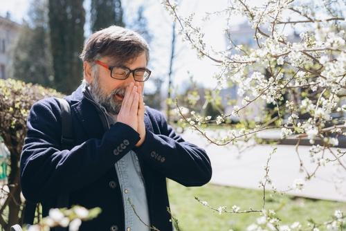 Senior man experiencing pollen allergy symptoms outdoors
