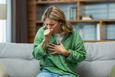 Woman in green coughing on living room