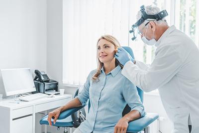 Doctor-examines-woman's-ear-in-medical-office.