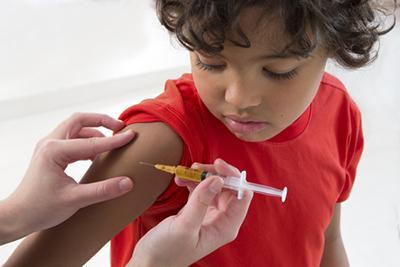 Young boy in red shirt receiving an immunization shot