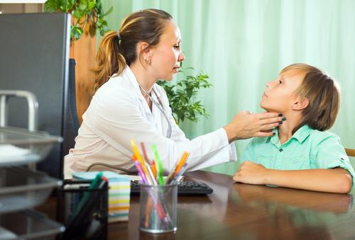 A pediatrician examining a child's neck to assess thyroid health.