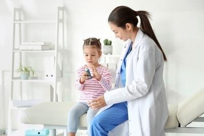 Young girl beside the doctor having an inhaler for asthma